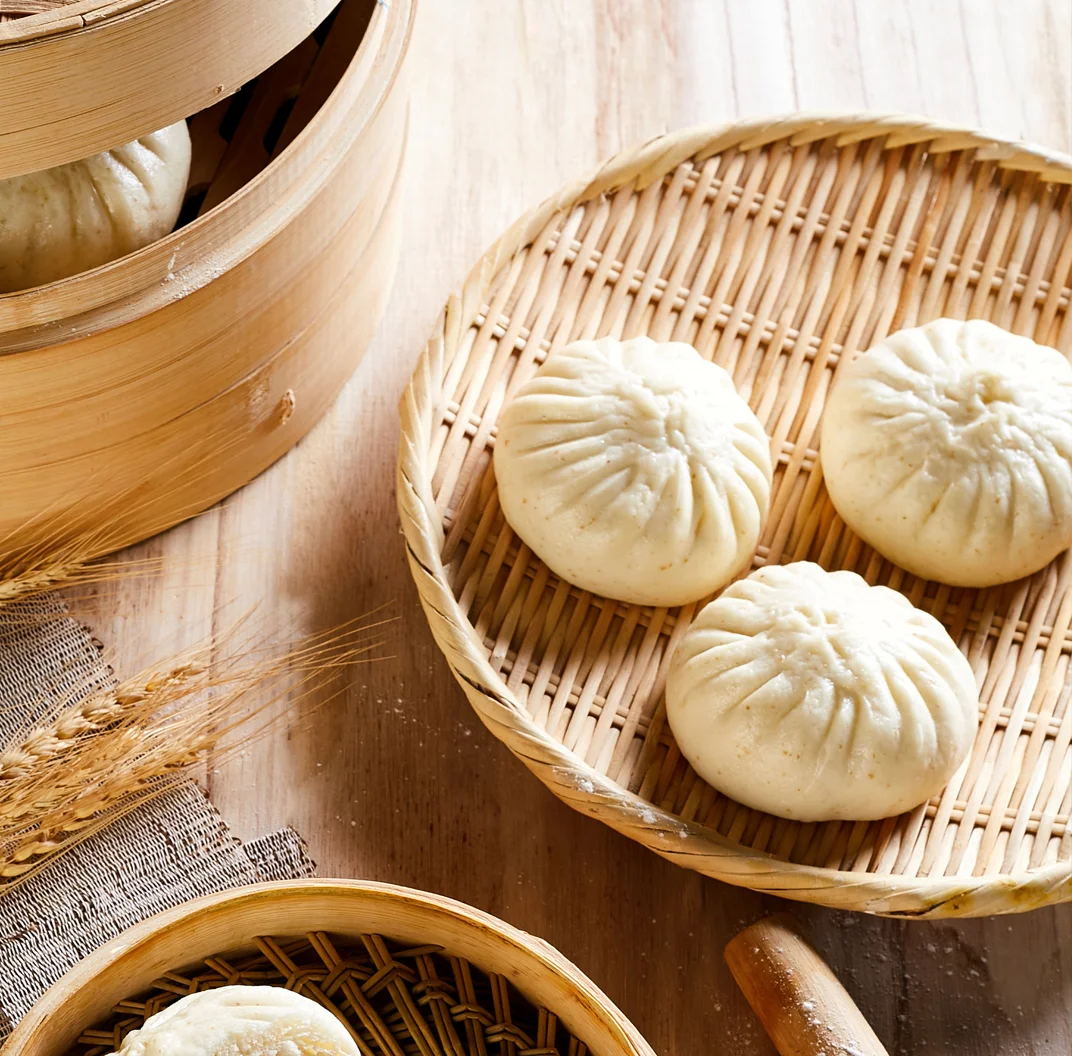 Chinese baozi steamed buns on a bamboo plate
