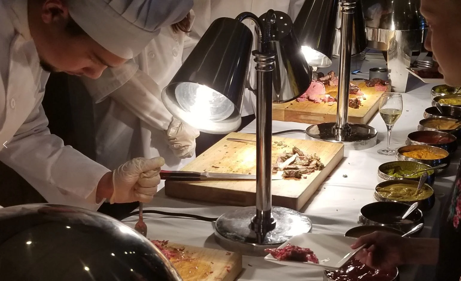 Chefs preparing gourmet dishes at a buffet station with various sauces