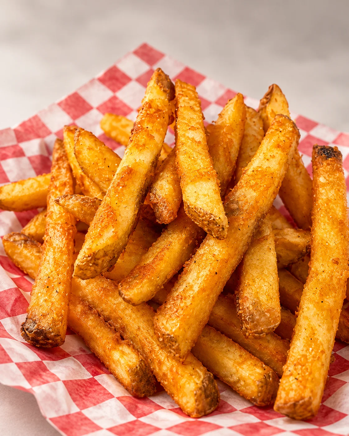 Crispy golden French fries served in a checkered paper basket