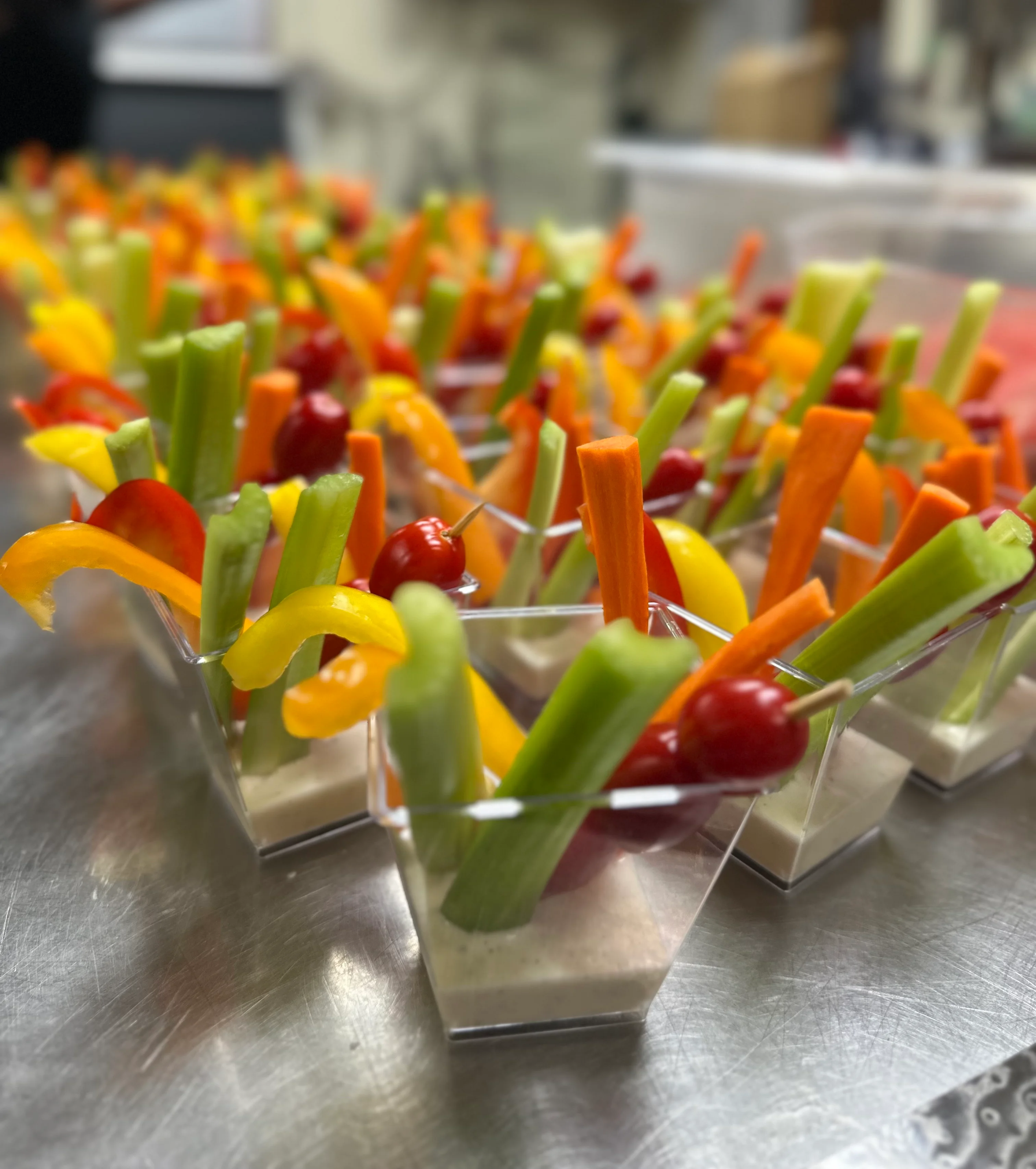 Colorful vegetable crudités with dip in clear cups
