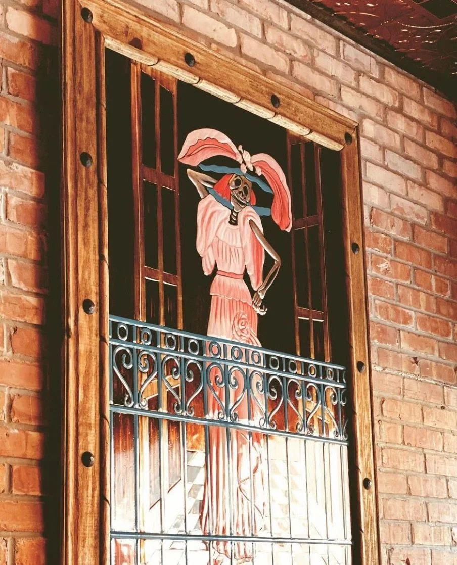 Colorful mural of a skeleton woman in a restaurant setting