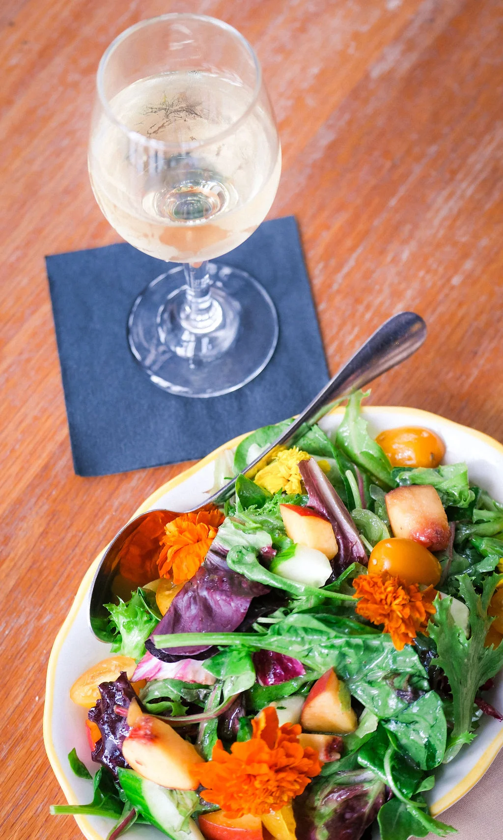 Fresh garden salad with edible flowers and white wine