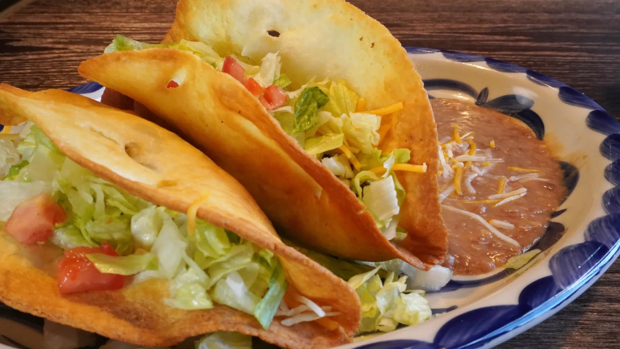 deep fried tacos that are homemade garnished with lettuce, cheese, tomato