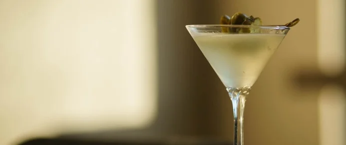 Classic martini cocktail with olive garnish on a polished bar