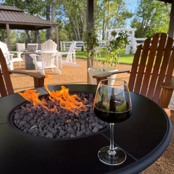 Glass of red wine beside a fire pit in a cozy outdoor setting