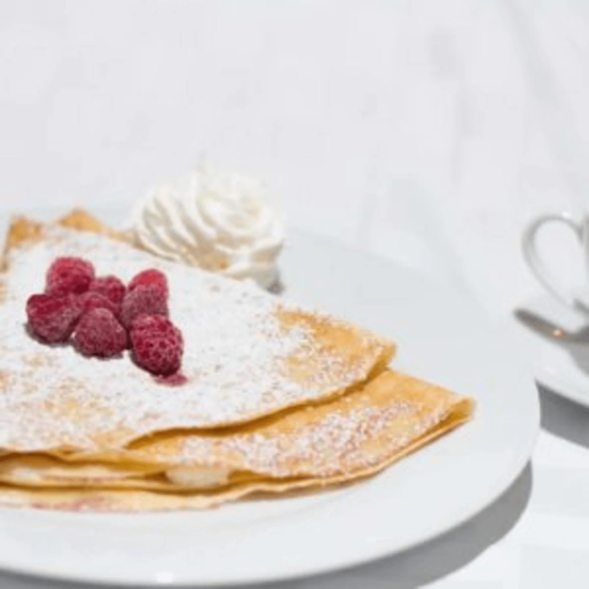 Delicious French crepes topped with raspberries and whipped cream