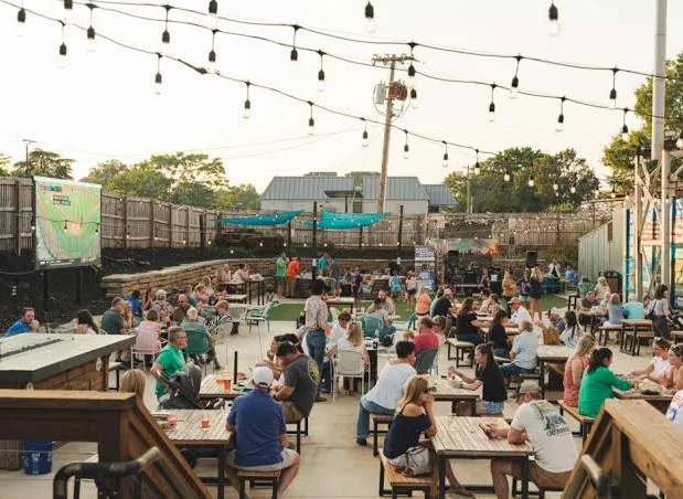 Outdoor dining area bustling with guests under string lights