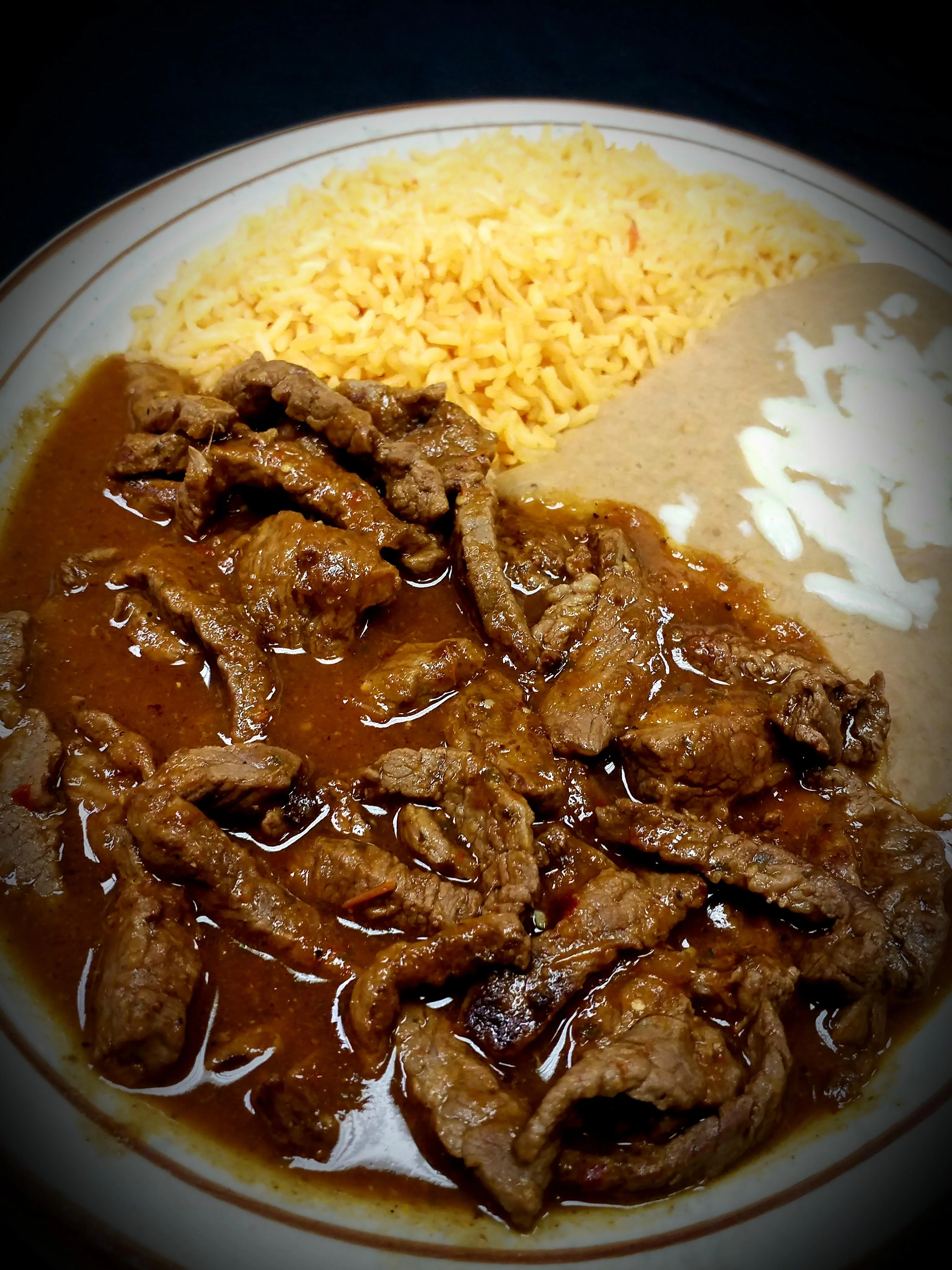 Experience the bold and spicy flavors of our Chile Colorado. Tender grilled steak simmered in a homemade spicy red tomatillo sauce, served with Mexican rice and creamy refried beans. A true taste of Mexico and a favorite in Radford.