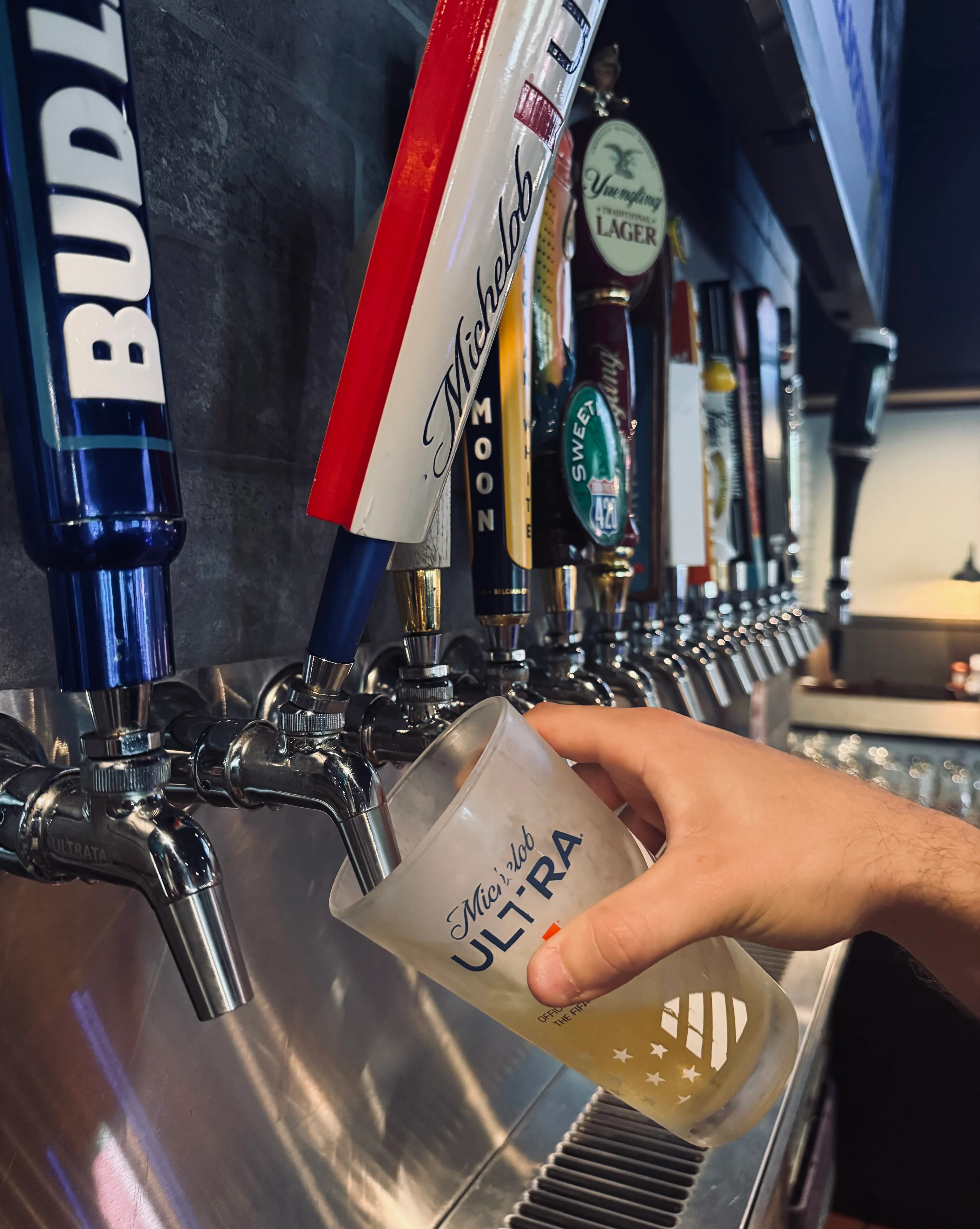 Bartender pouring a cold beer from a tap at a lively bar