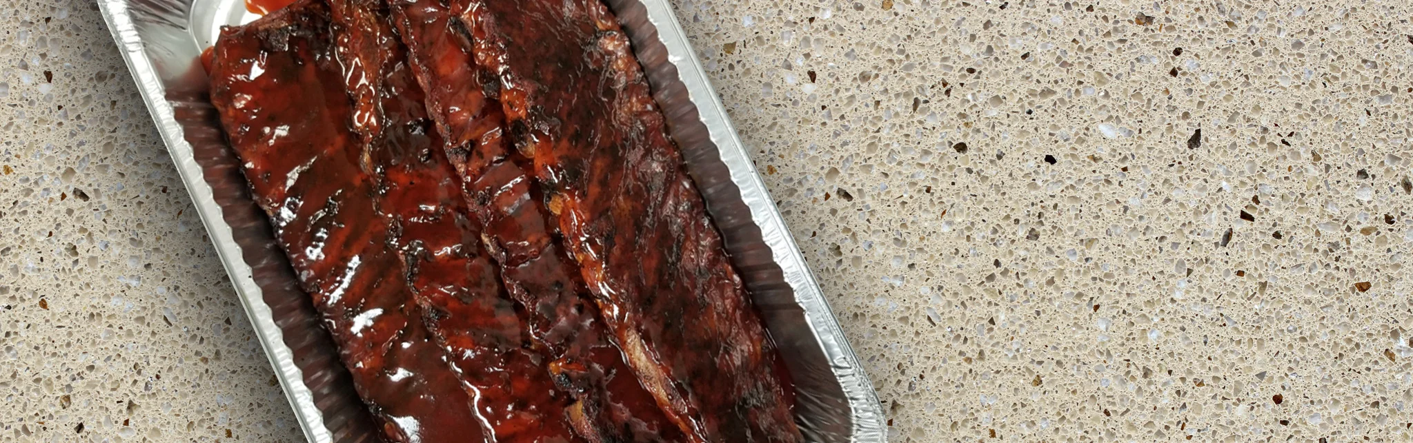 BBQ ribs glazed with sauce in a metal tray