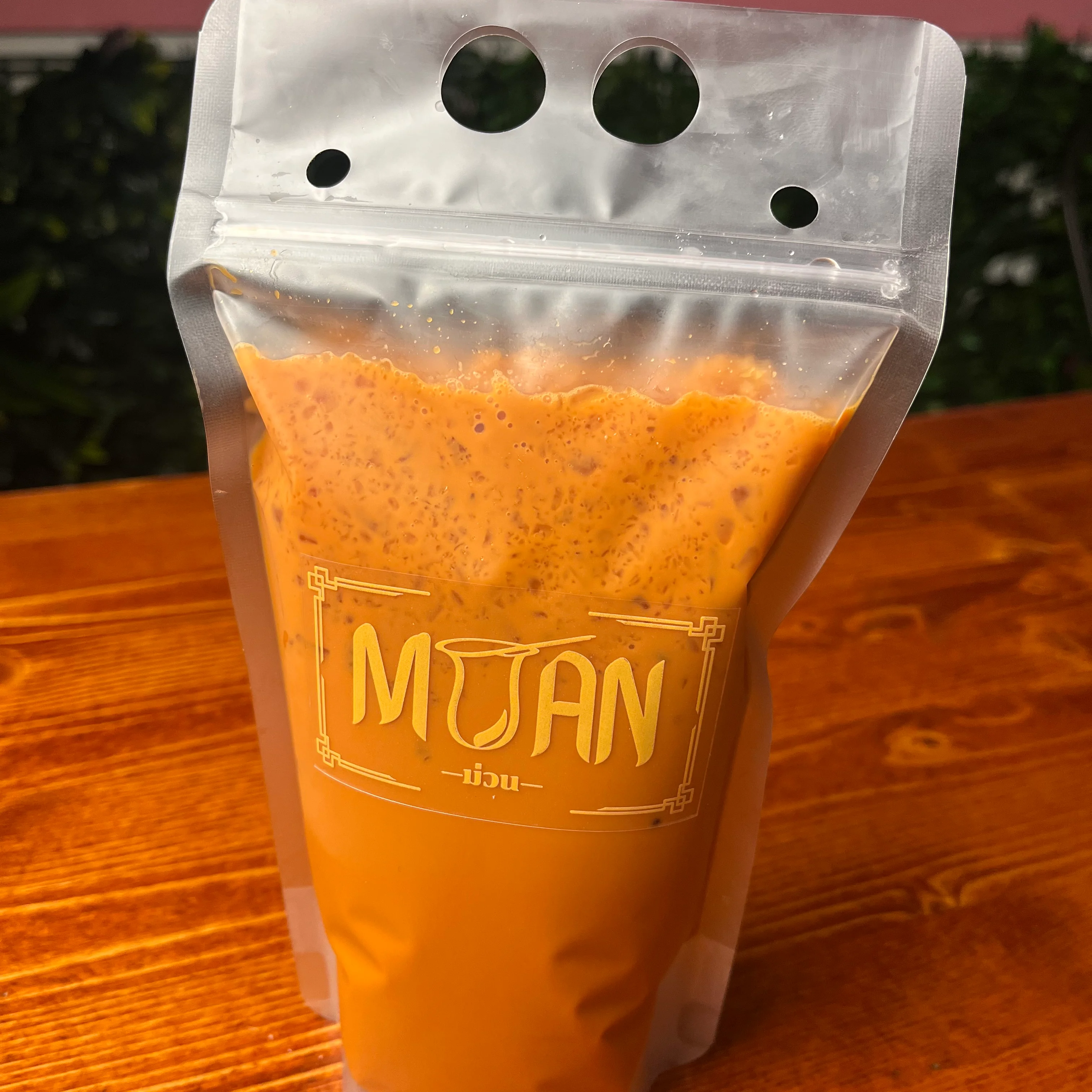 A refreshing beverage in a clear cup, featuring a reddish-brown drink topped with ice and a slice of lime.