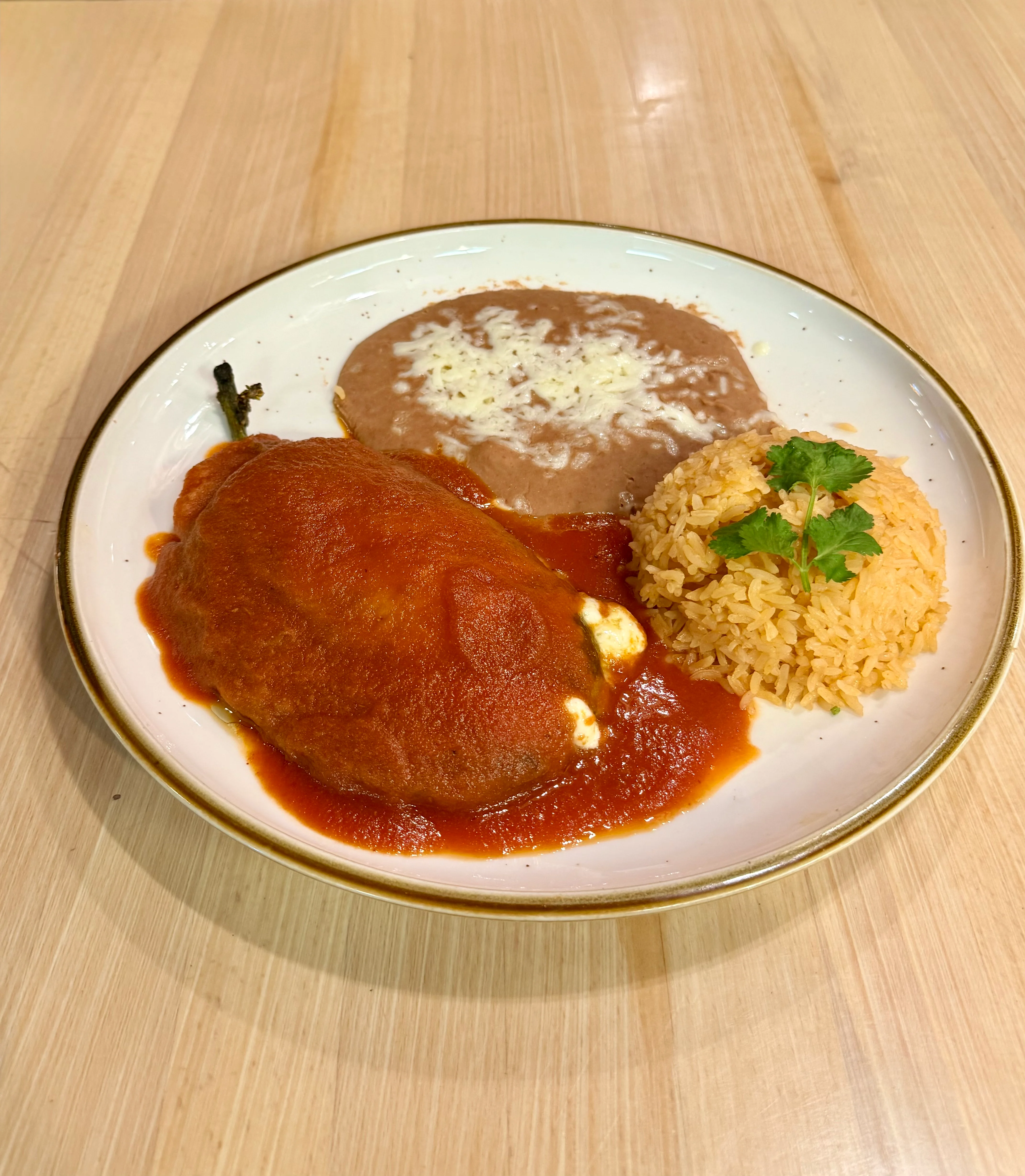 Chiles Rellenos with rice and refried beans on a plate