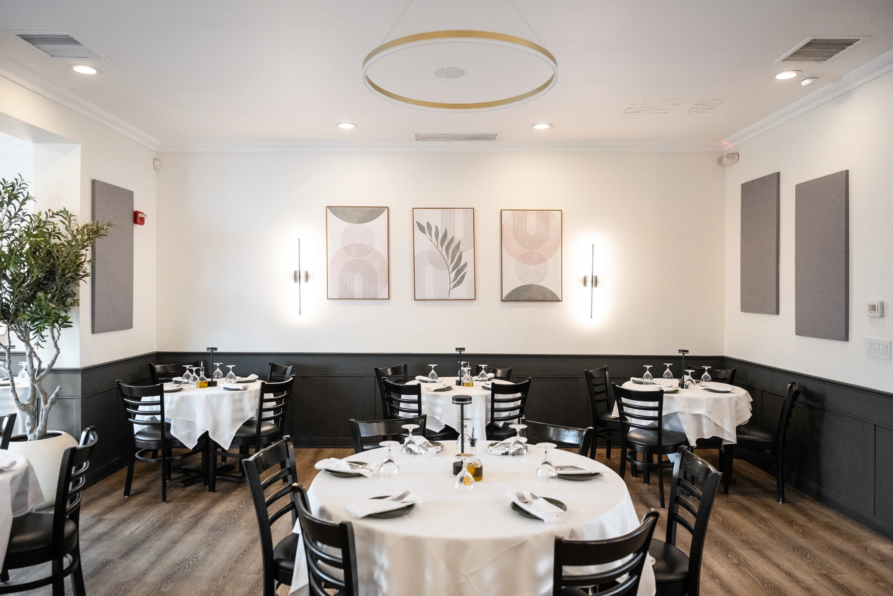 Private dining setup at Toscana on Main Eastchester featuring round tables, stylish decor, and modern art on the walls, perfect for dining experiences.