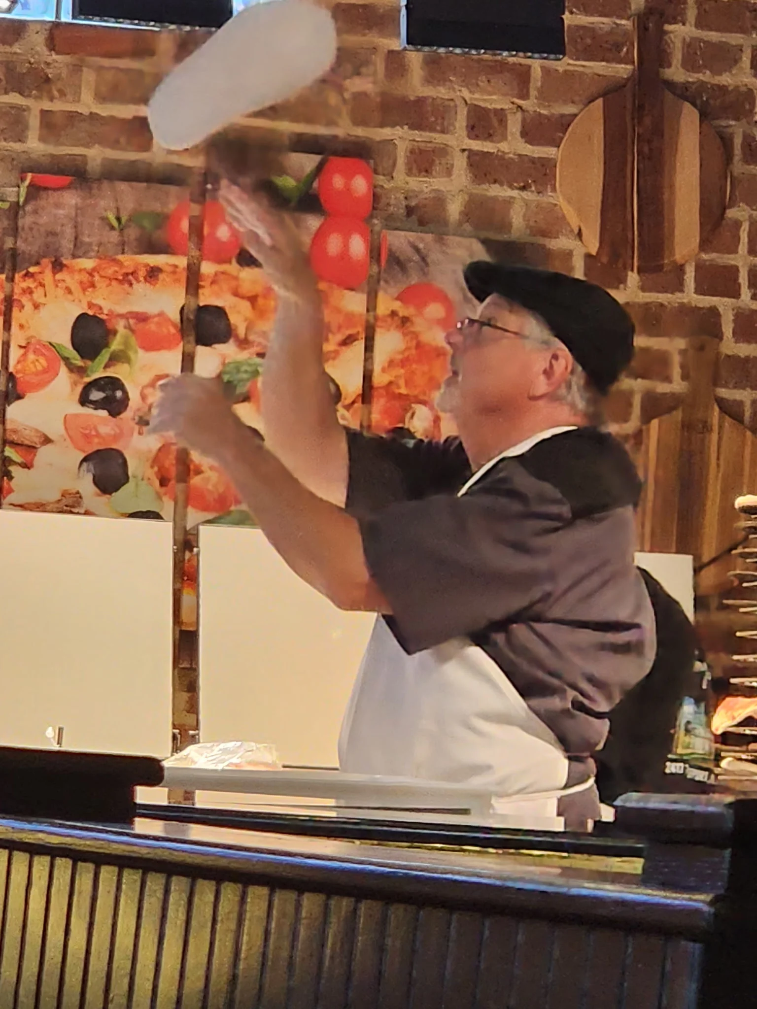 Chef tossing pizza dough in a lively restaurant