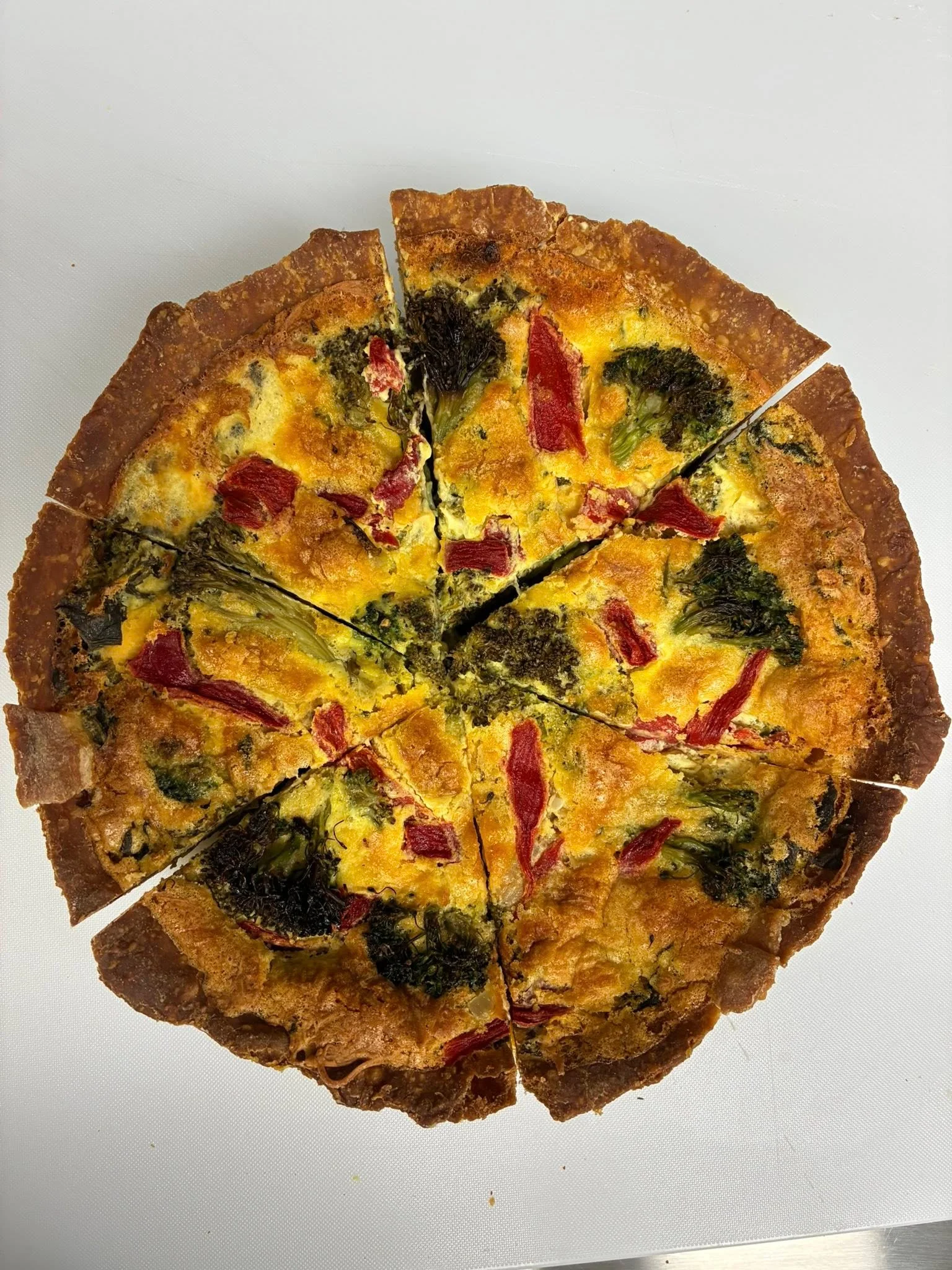 Vegetable frittata sliced into pieces on a white surface.