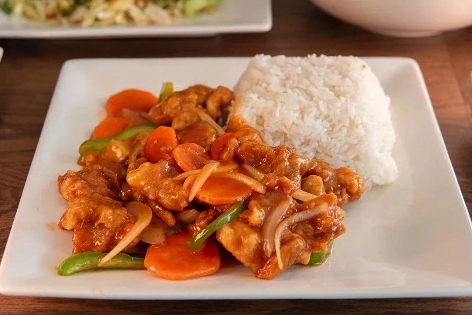Sweet and sour chicken with rice on a white plate