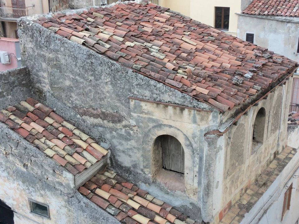 An old building with a weathered exterior and a tiled roof. The structure displays a rustic charm with its rough walls and visible wear.
