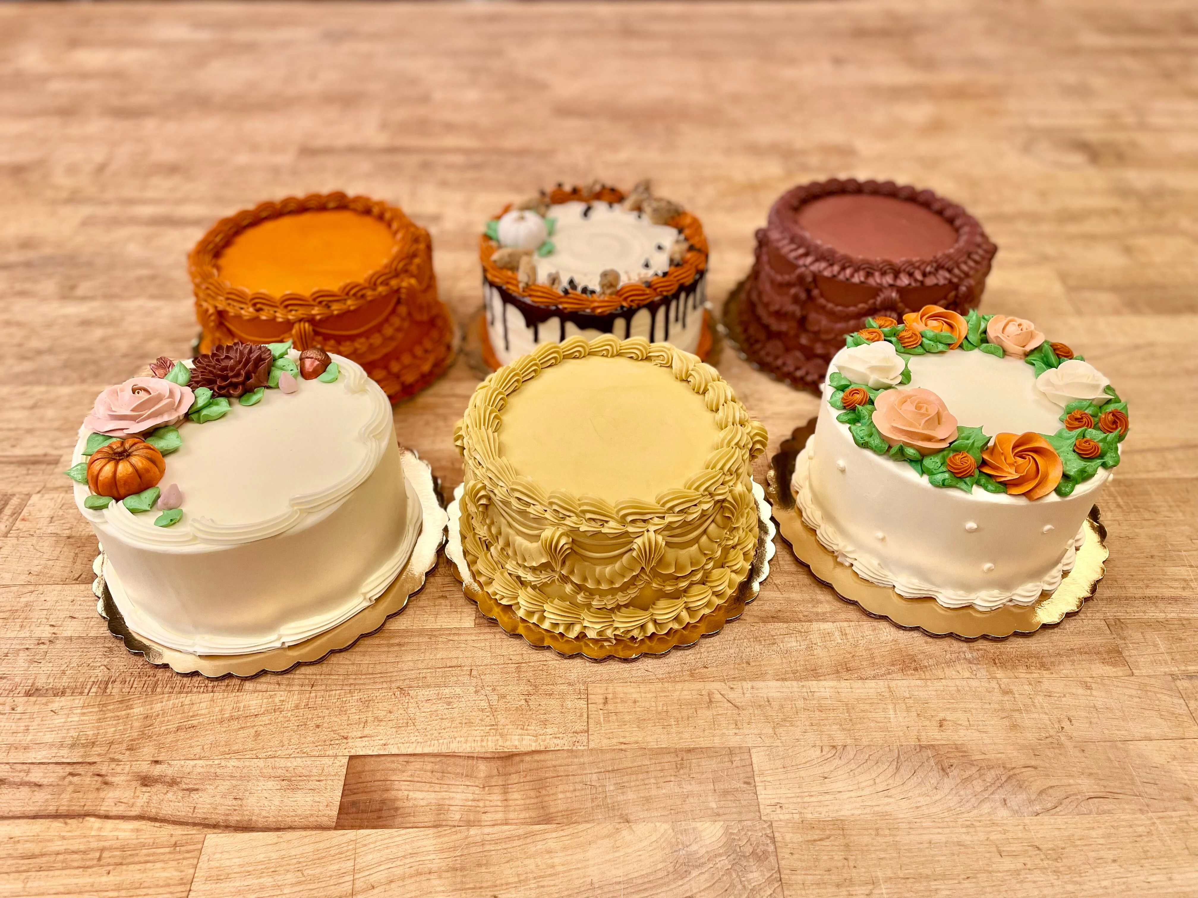 Assortment of beautifully decorated buttercream celebration cakes on a wooden table