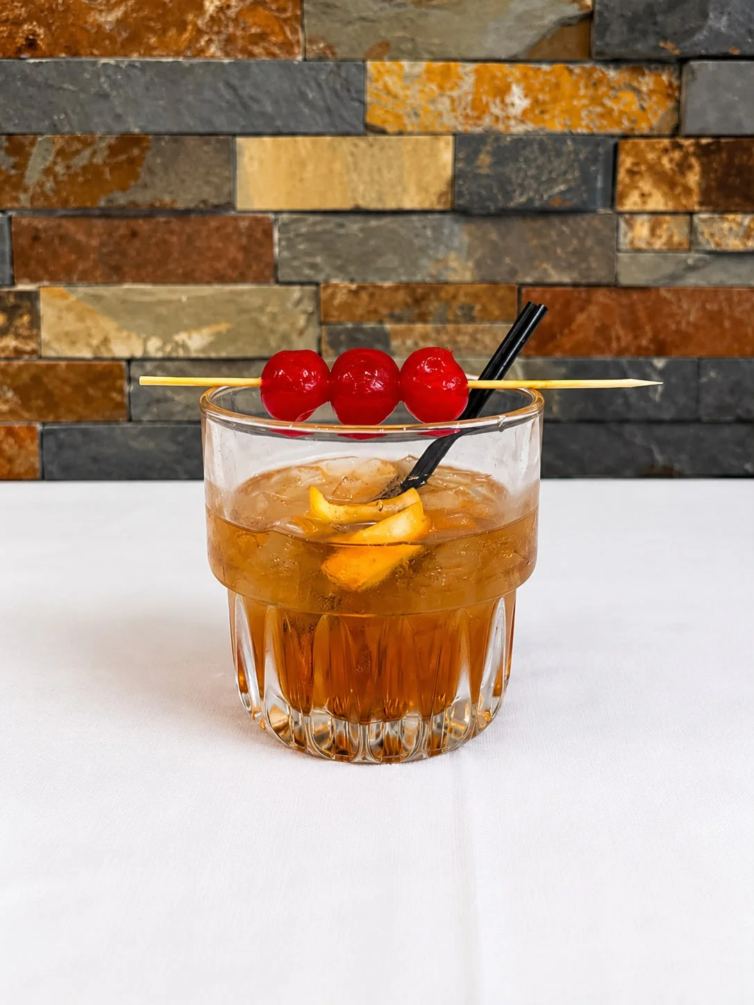 Classic Old Fashioned cocktail with cherries and orange garnish