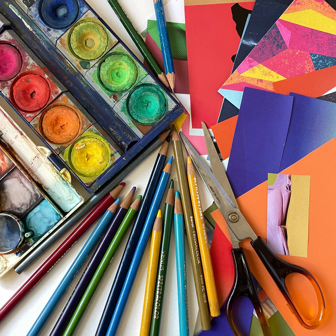 Crafting session with colorful paper, snacks, and drinks on a wooden table.