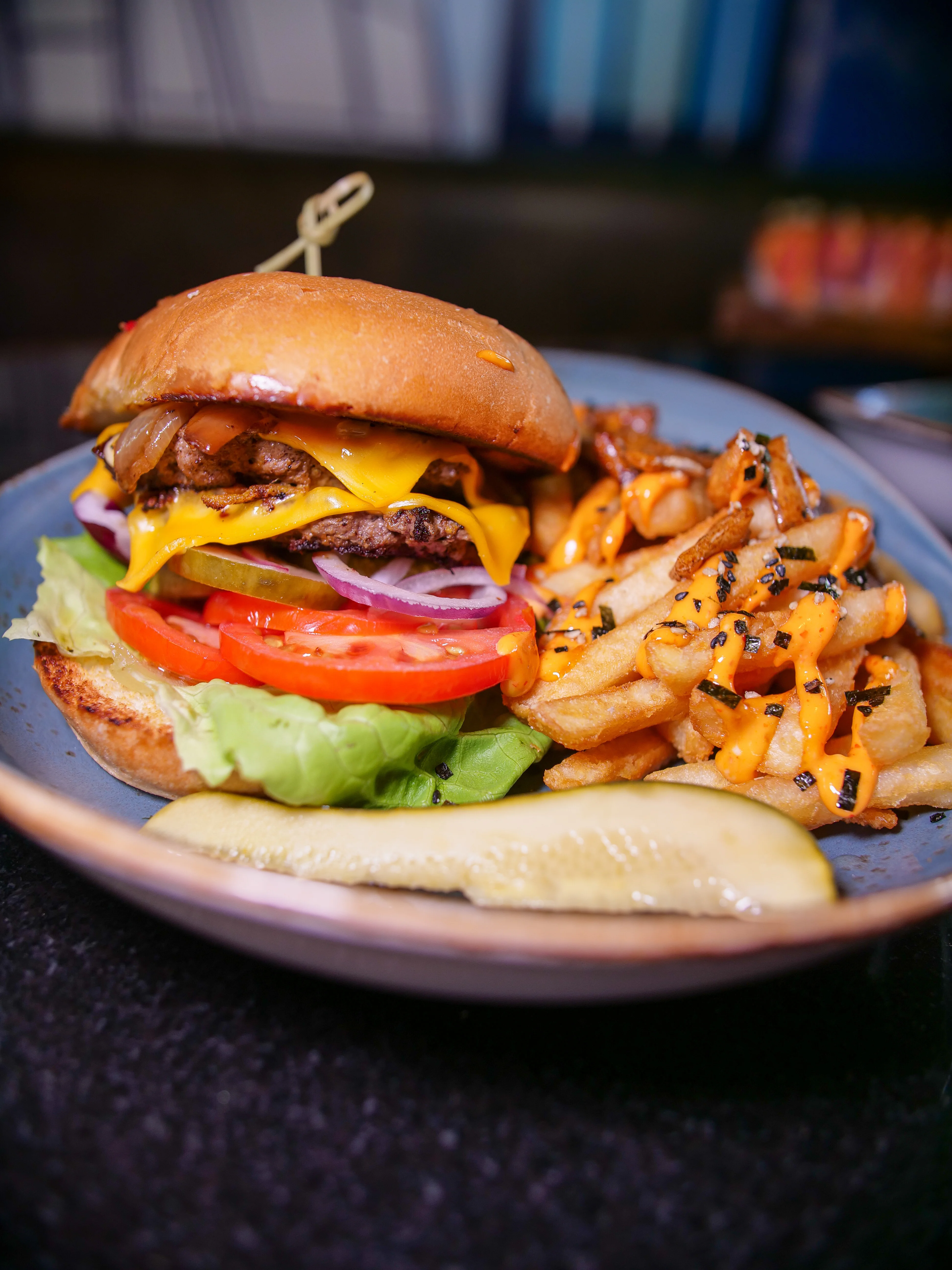 Juicy cheeseburger with fries and pickles on a plate