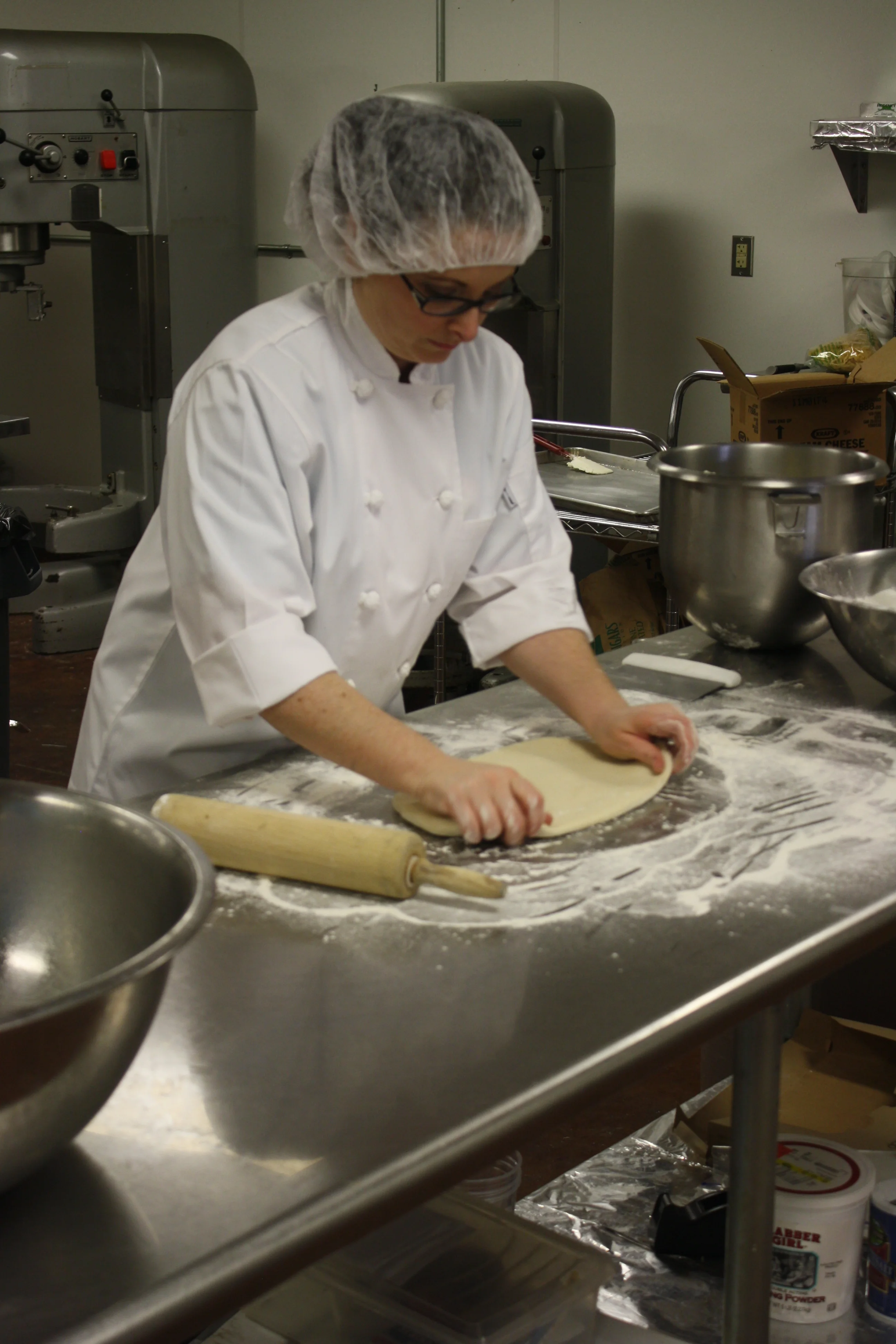 Baker rolling dough in a professional kitchen