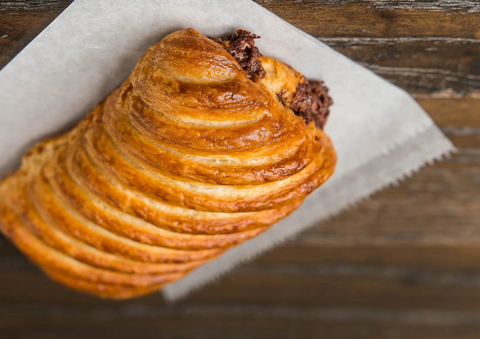 Freshly baked chocolate croissant on parchment paper
