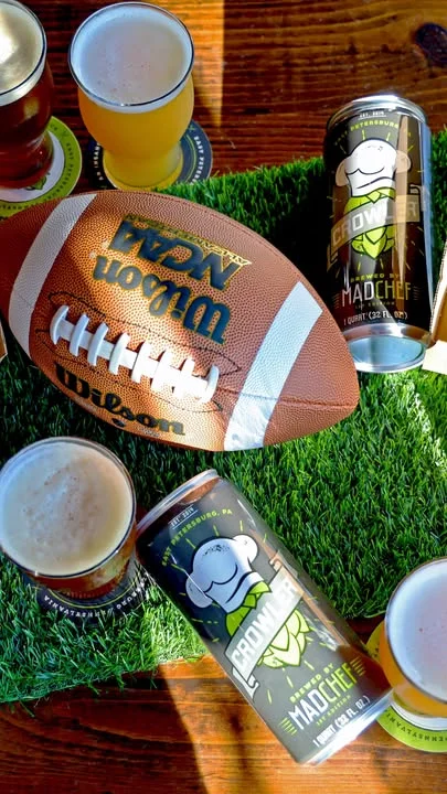 Football and craft beer cans on a grassy table