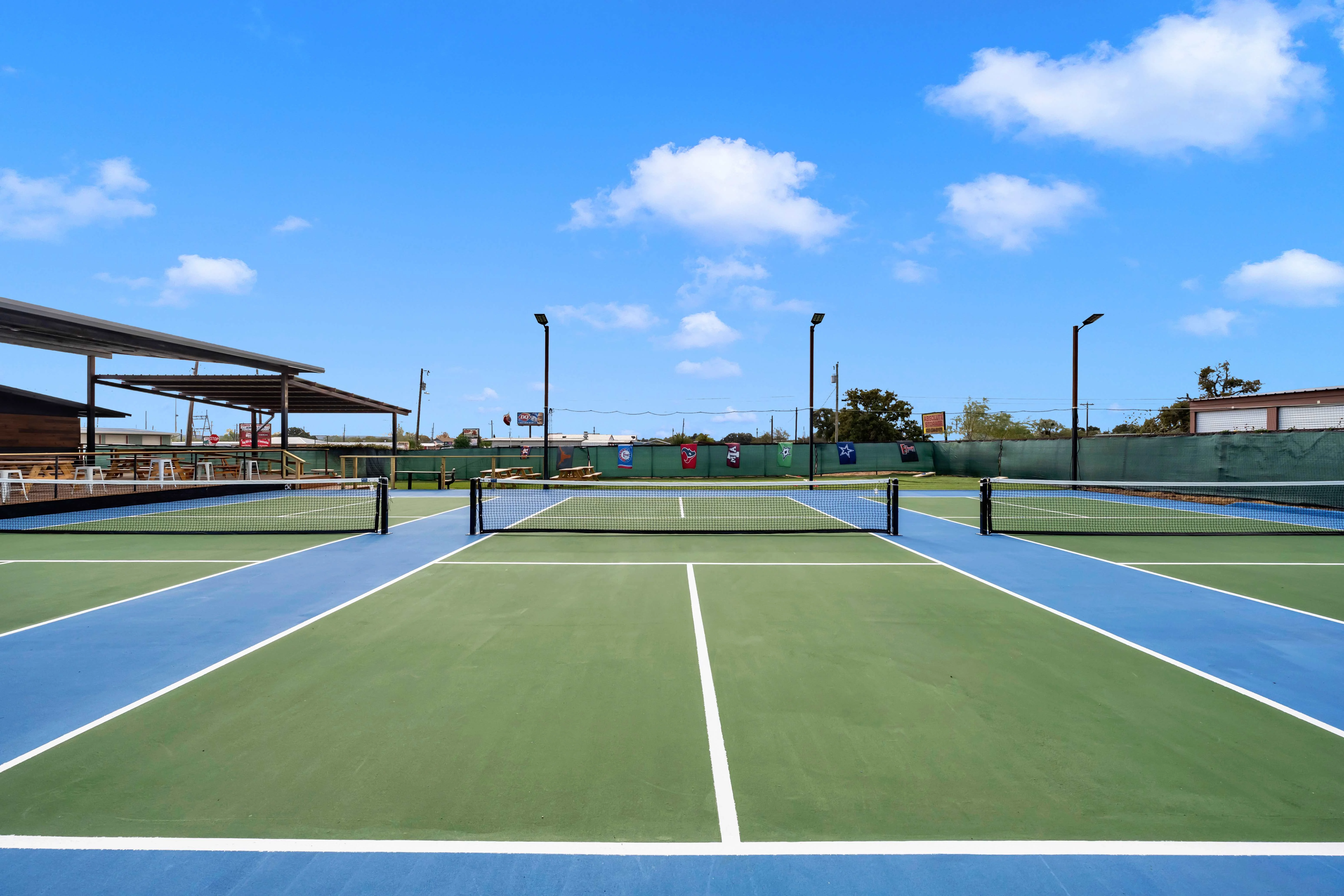Outdoor dining area with picnic tables and pickleball courts