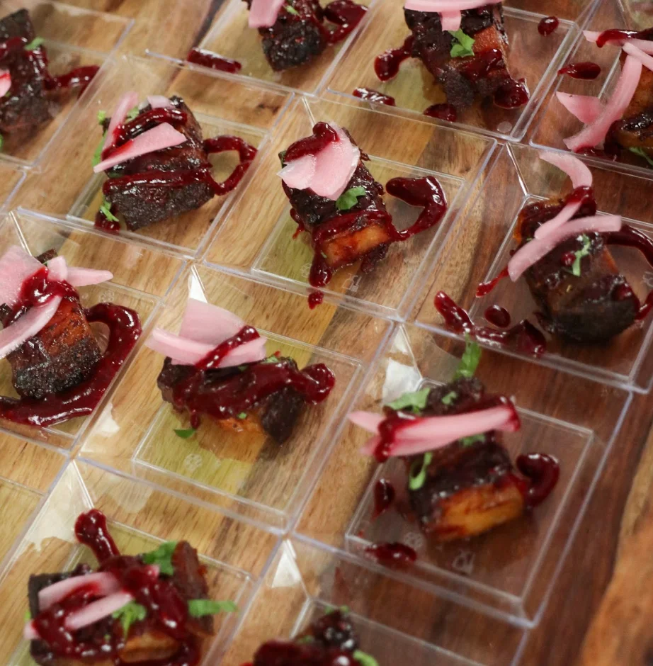 Gourmet dish served in clear containers with sauce and garnishes.