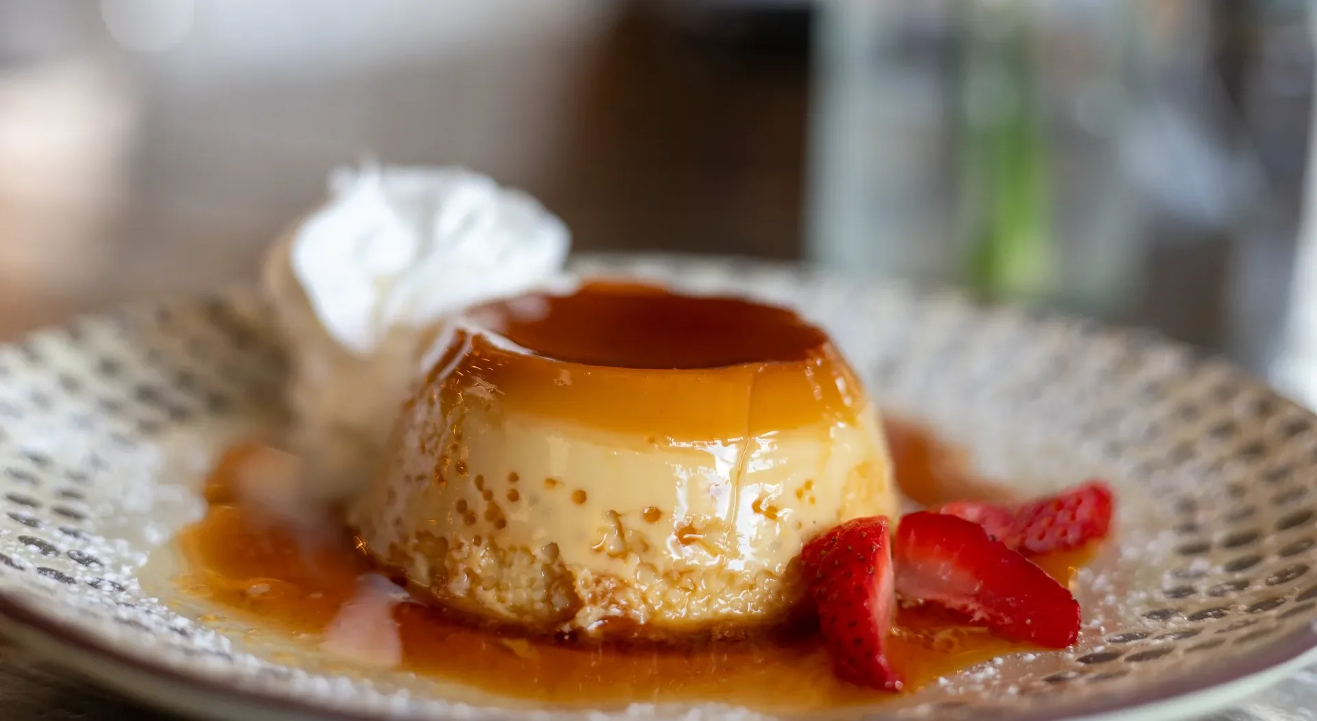 Classic flan dessert with caramel sauce and strawberries