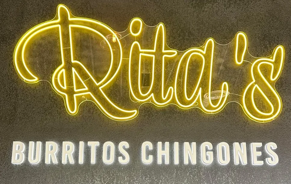A neon sign displaying the name of a burrito restaurant, with vibrant lighting.
