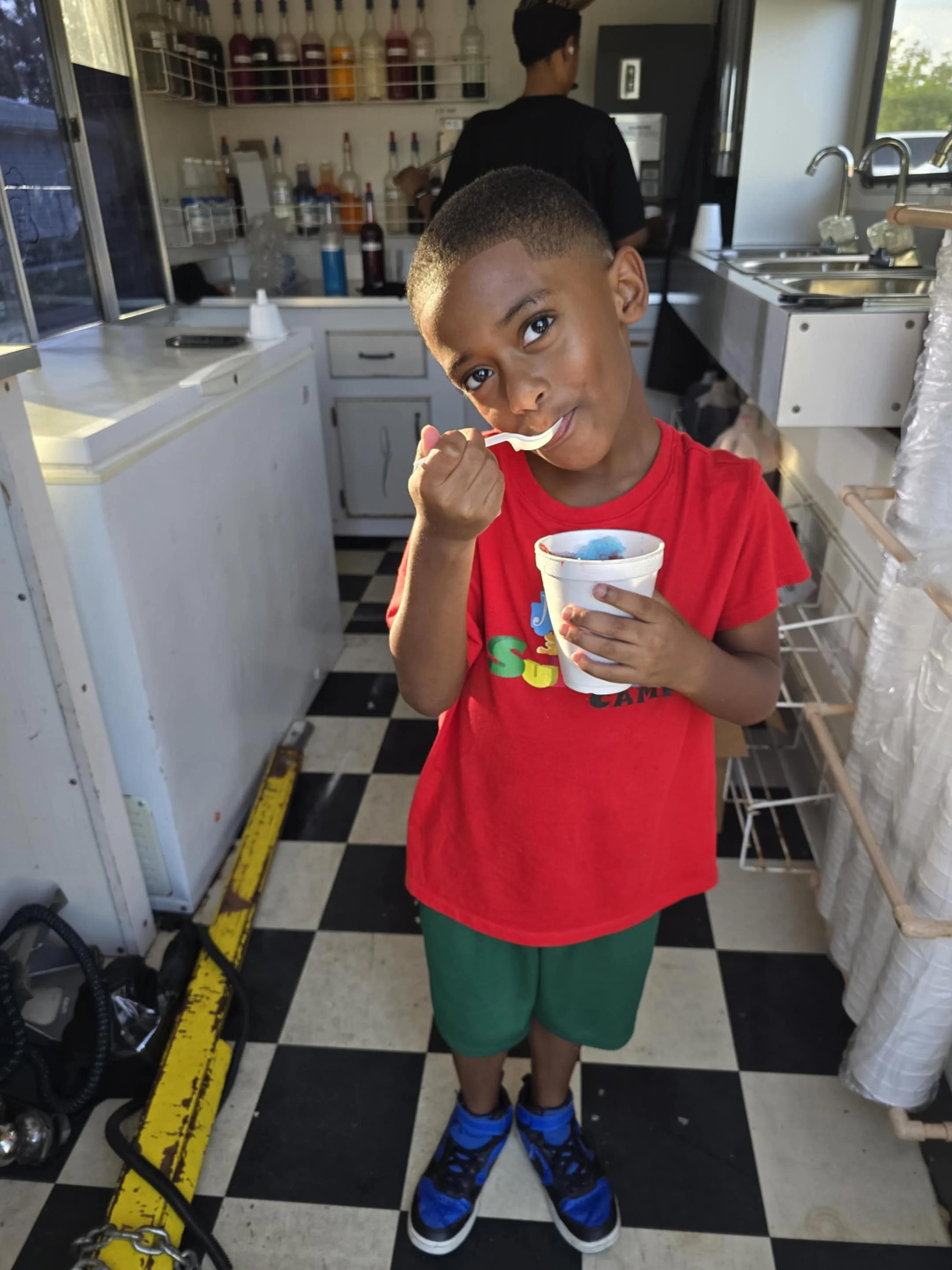 Child enjoying a colorful snow cone in a vibrant food truck