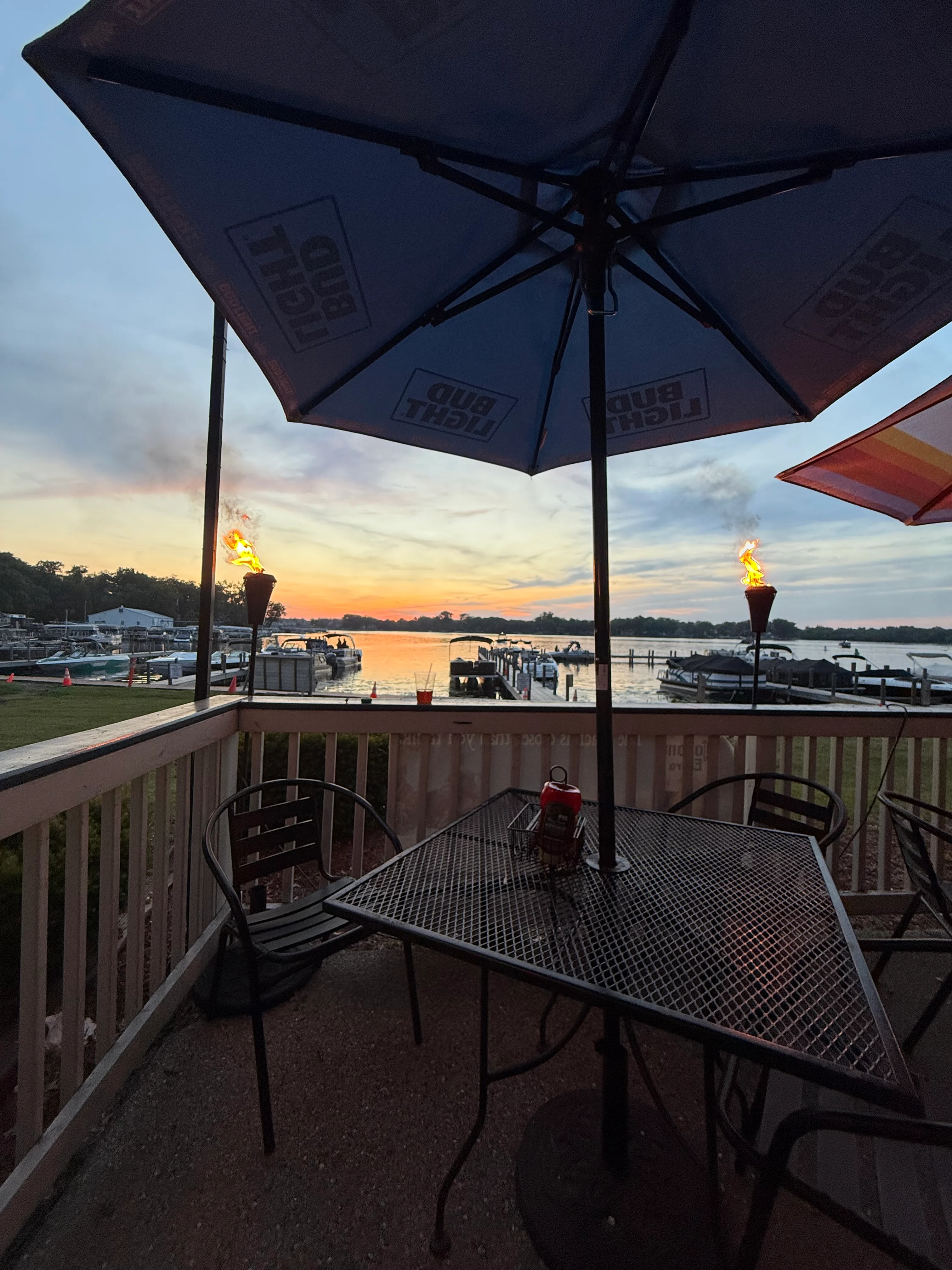 Patio table under an umbrella looking out at the dock and Bluff Lake at sunset