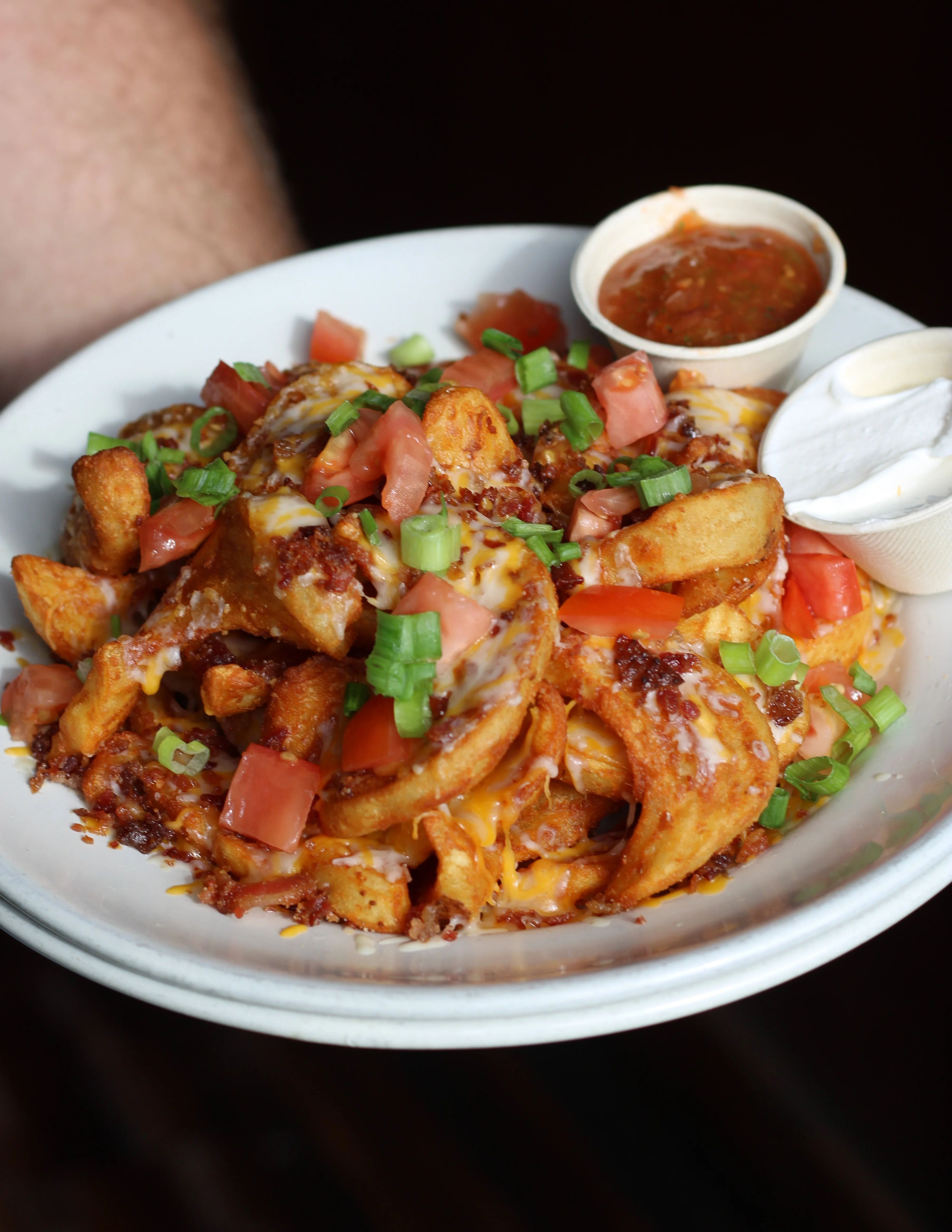 Loaded potato wedges with cheese and toppings, served with salsa and sour cream