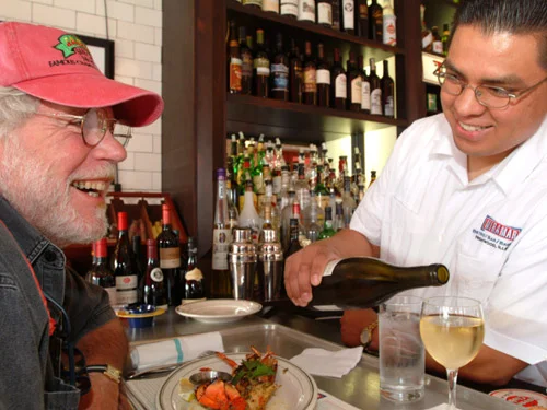 Friendly waiter pouring wine at a restaurant table