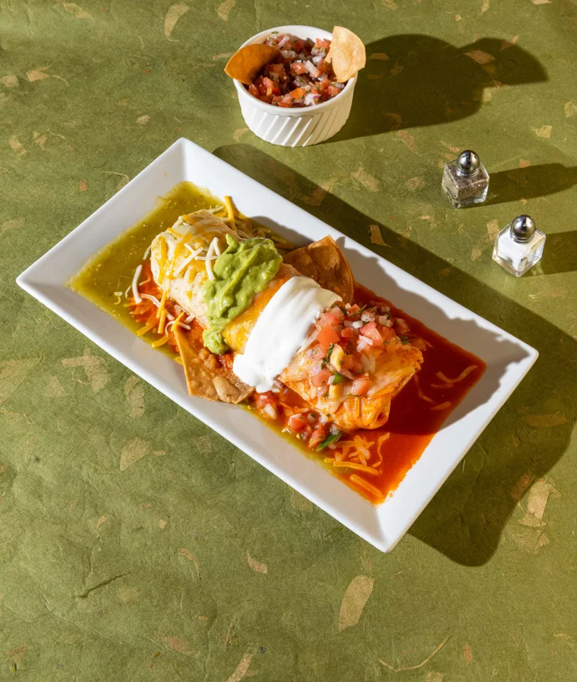 Mexican Flag Burrito served with guacamole, sour cream, pico de gallo, and colorful sauces at Friducha in Brooklyn, NY.