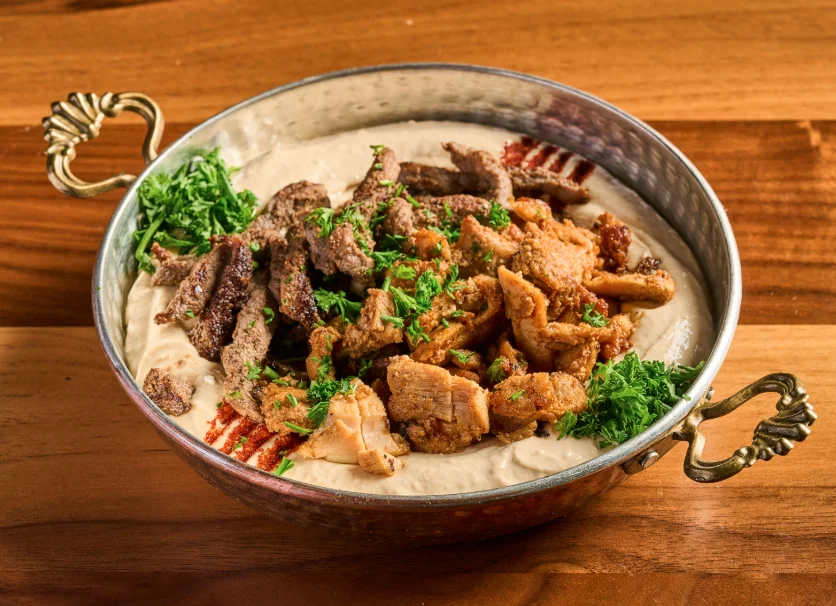 Hummus Shawarma topped with shawarma meat and sauces.
