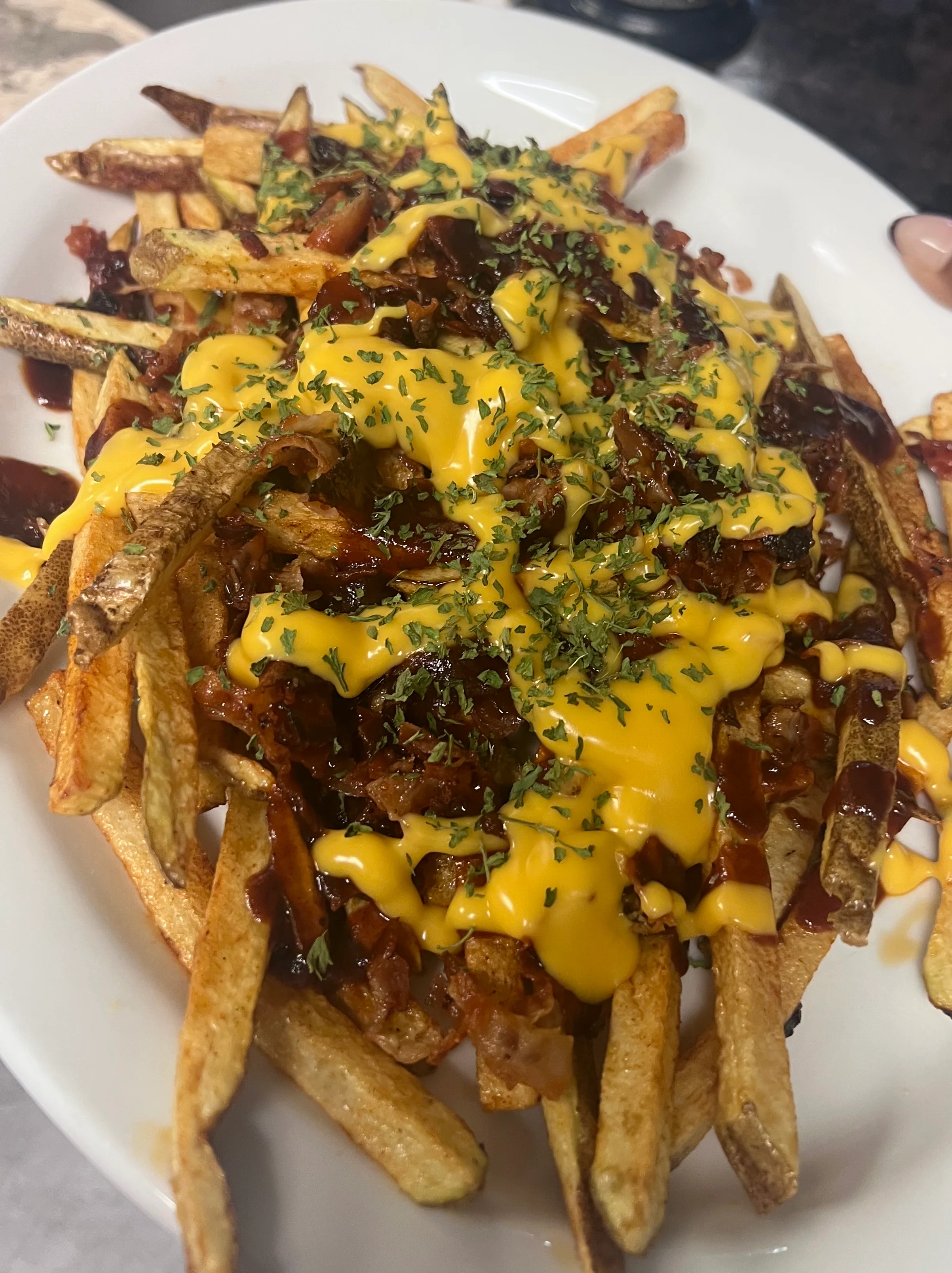 Loaded cheese fries topped with bacon and herbs, a classic comfort food dish