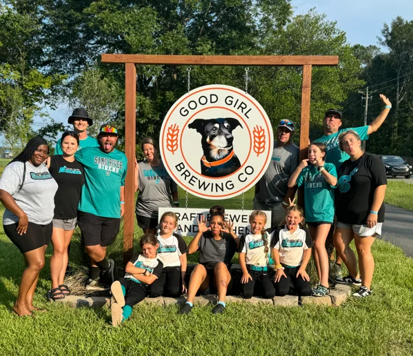 Group photo at Good Girl Brewing Co. with brewery sign