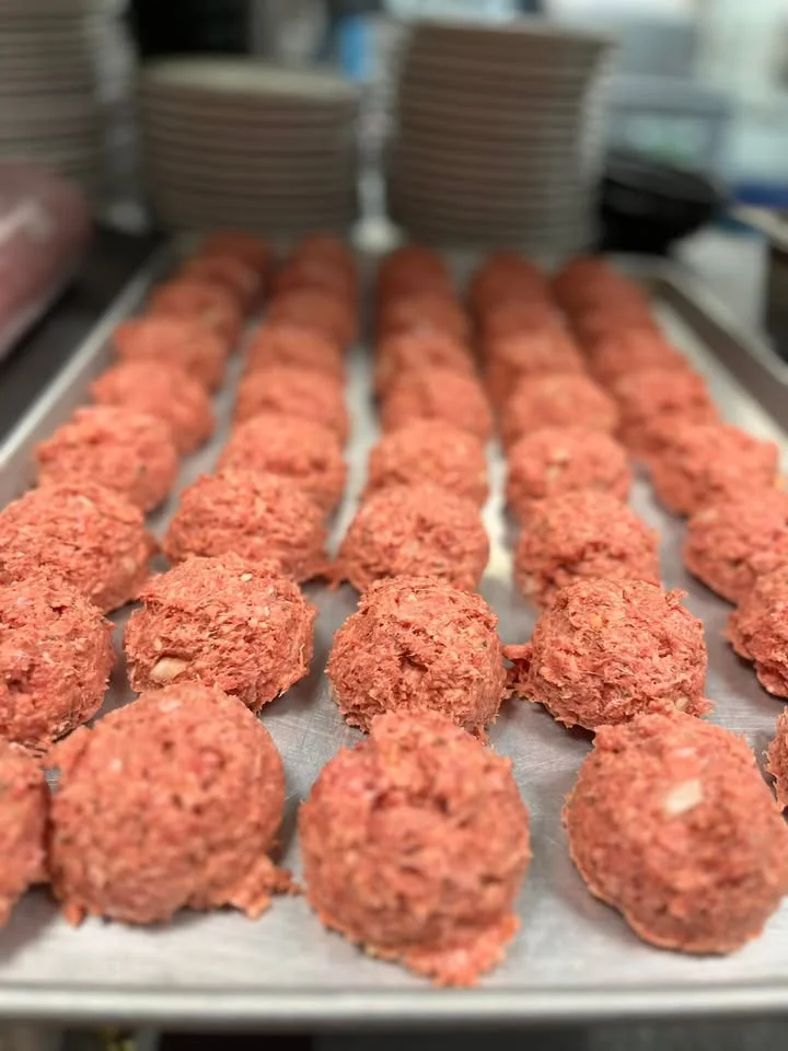 A tray filled with evenly shaped meatballs, ready for cooking, lined up in neat rows.