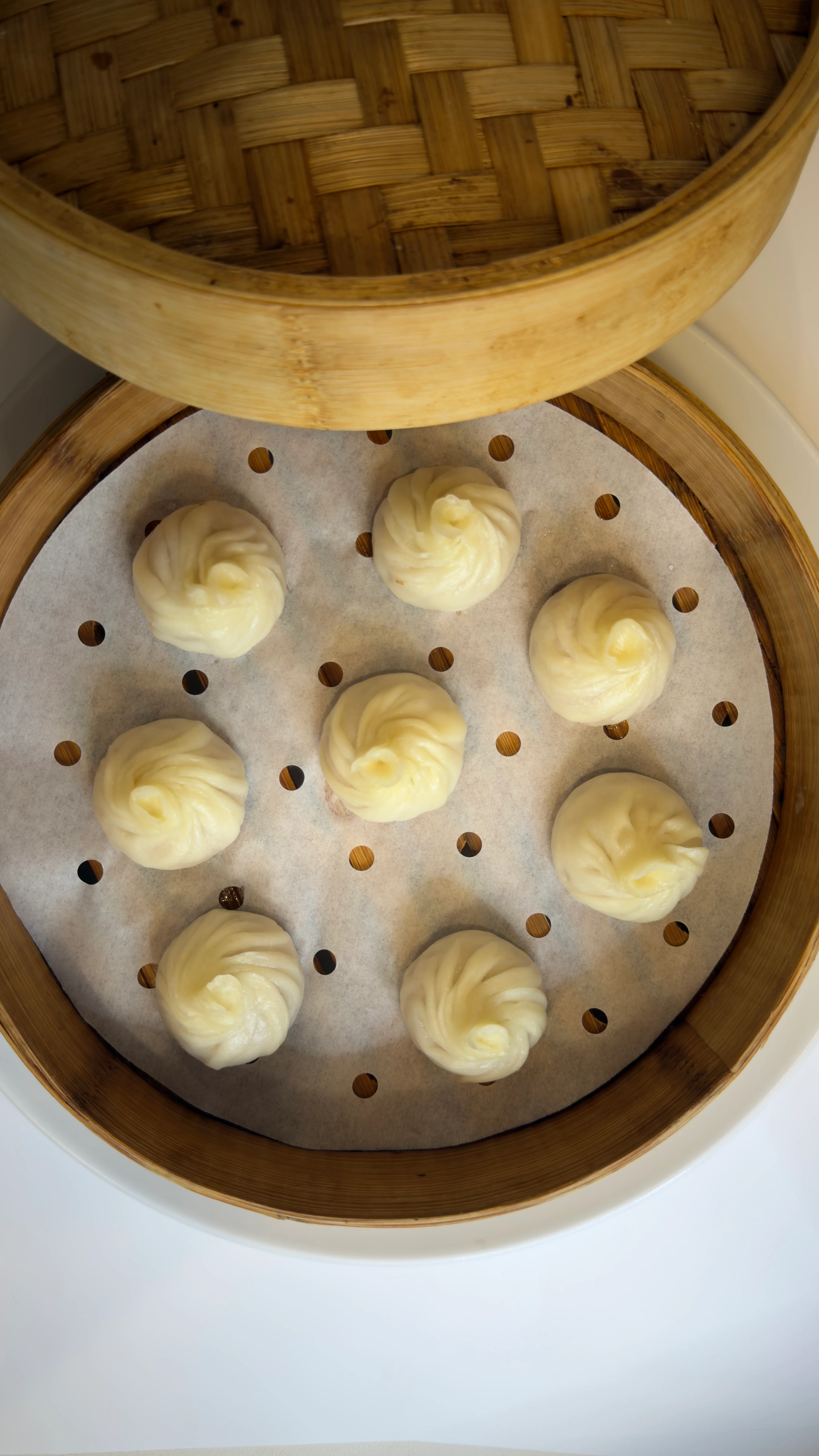 A bamboo steamer filled with vibrant green dumplings, neatly arranged on a parchment-lined base, showcasing their unique shape.