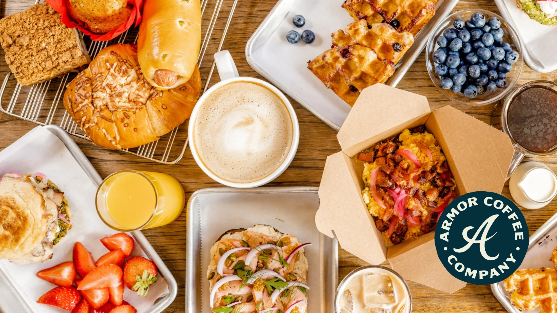 A beautifully arranged spread of breakfast items including pastries, a sandwich, fresh strawberries, and various drinks like coffee and juice. The vibrant colors and variety highlight a delightful breakfast experience.