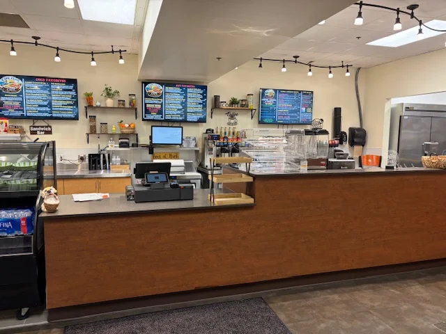 Interior of a restaurant with a counter, menu boards, and seating area.