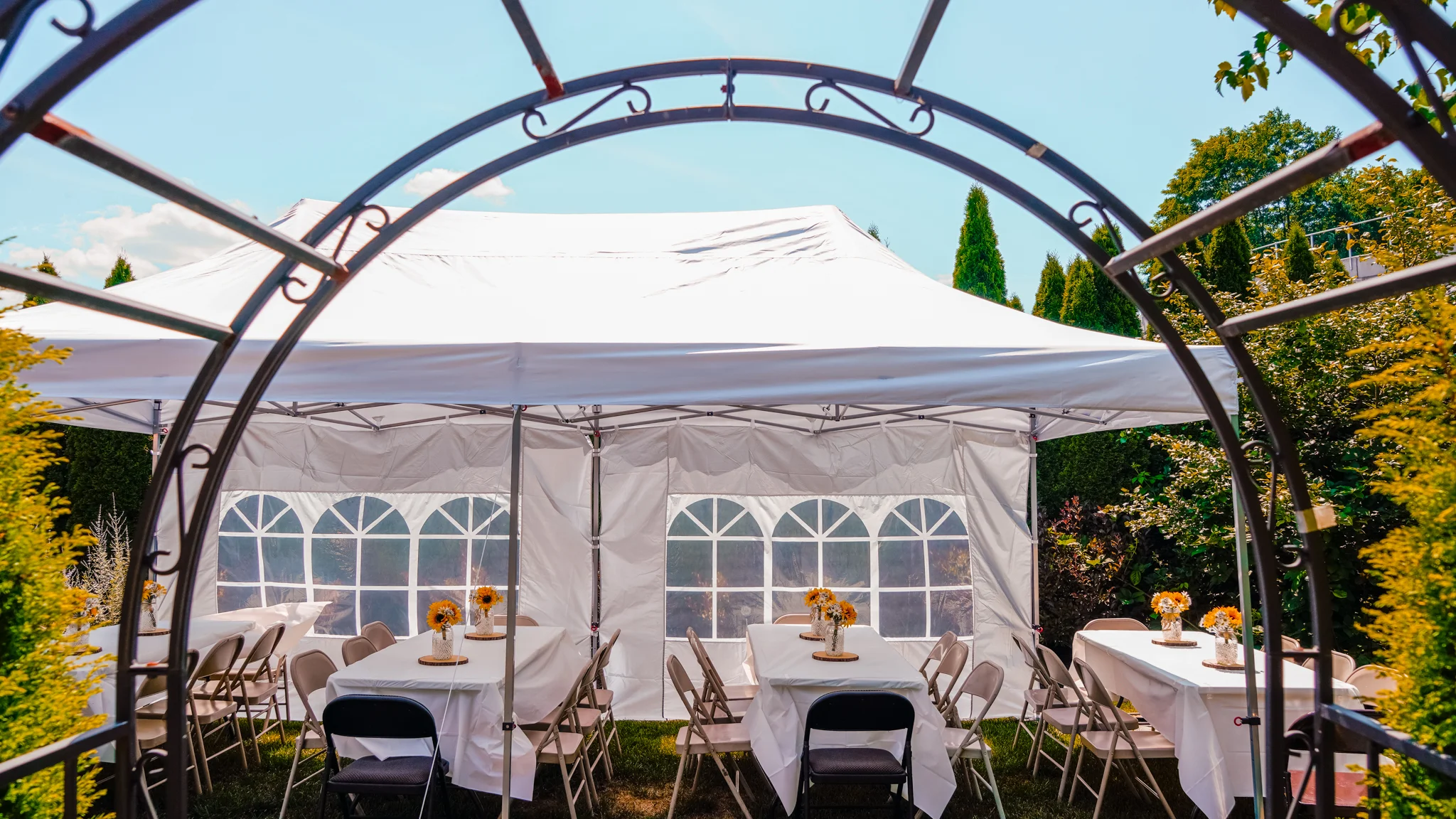 Outdoor dining setup under a white tent with tables and sunflowers