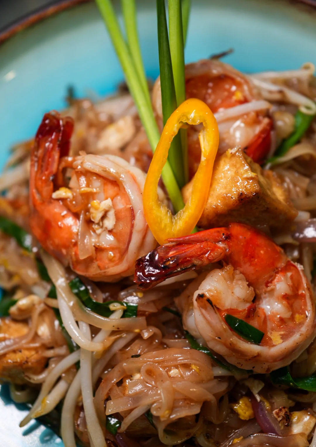 Delicious shrimp pad thai garnished with green onions and peppers