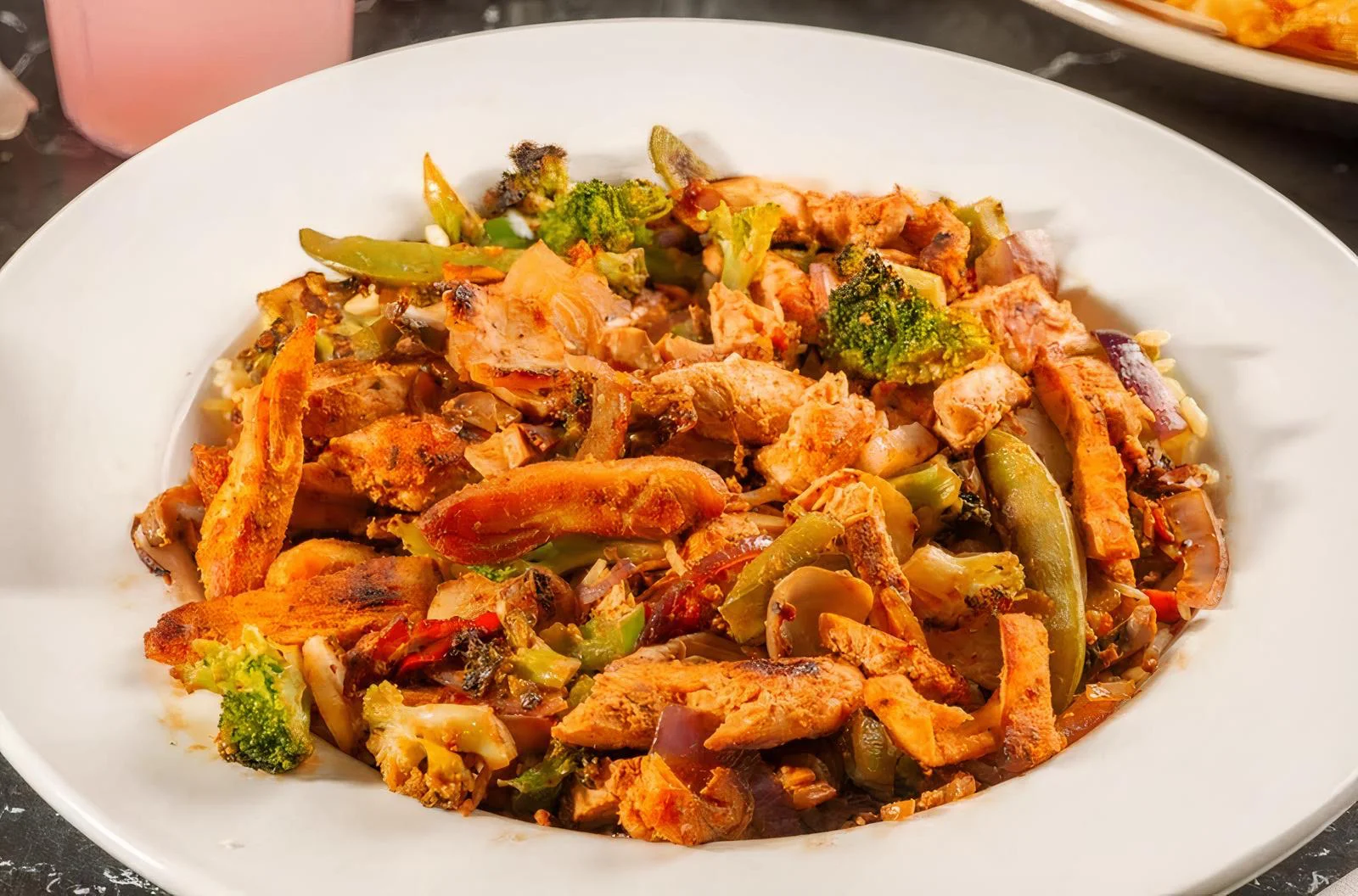 Sizzling chicken stir-fry with vegetables in a white bowl