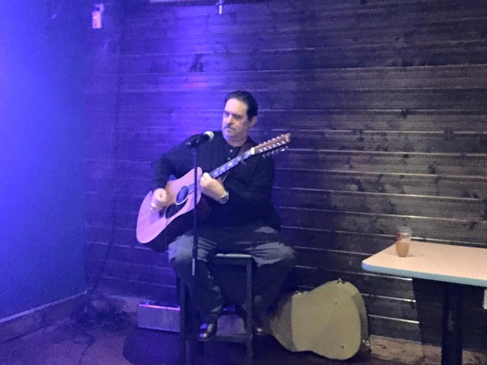 Musician performing live with acoustic guitar in a cozy venue