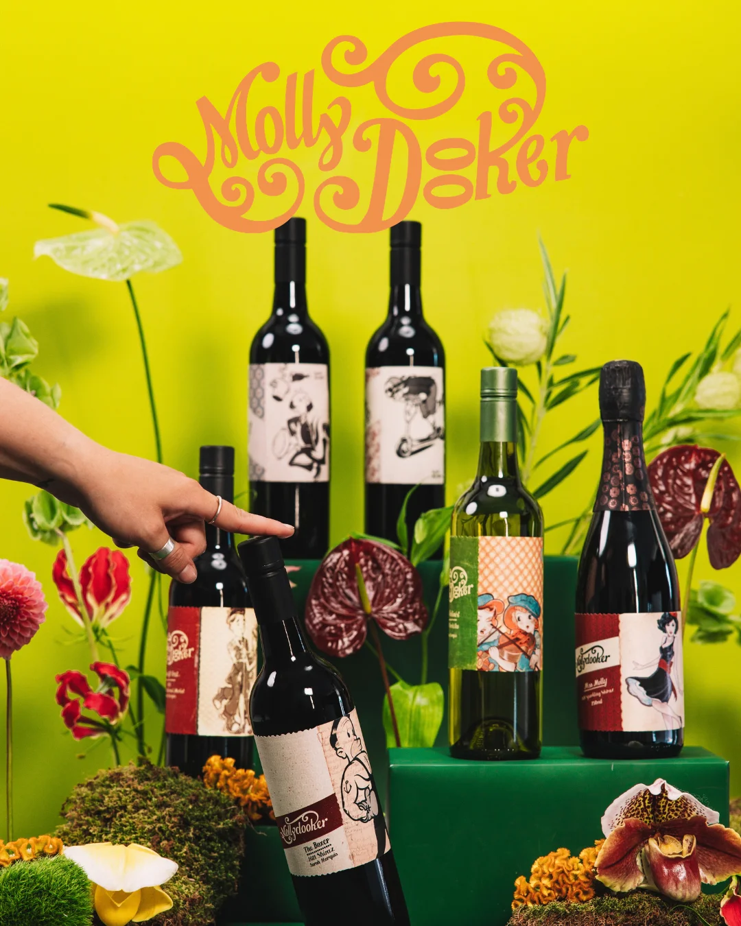 Artfully arranged wine bottles with floral botanical display and restaurant branding