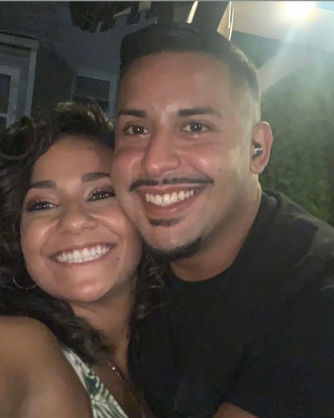 Happy couple smiling for a selfie outdoors at night
